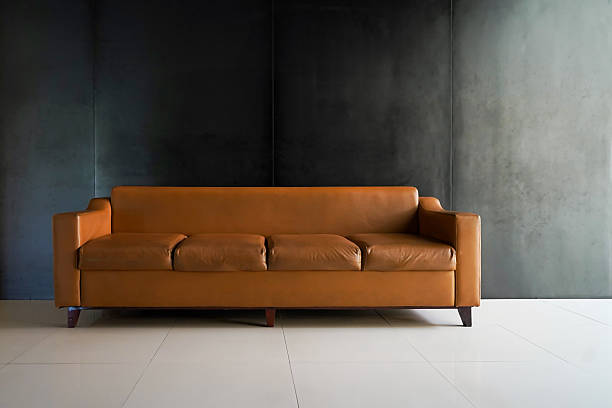 istock Modern Brown Leather Sofa Against Dark Wall in Minimalist Interior 2213543420