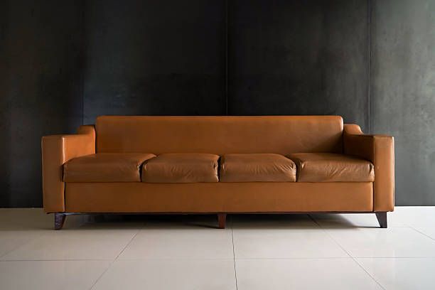 istock Modern Brown Leather Sofa Against Dark Wall in Minimalist Interior 2213543423