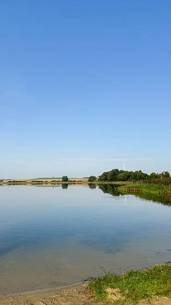 istock Serene lakeside landscape with clear blue sky and verdant greenery reflecting tranquility and natural beauty in a peaceful, scenic view 2213543458