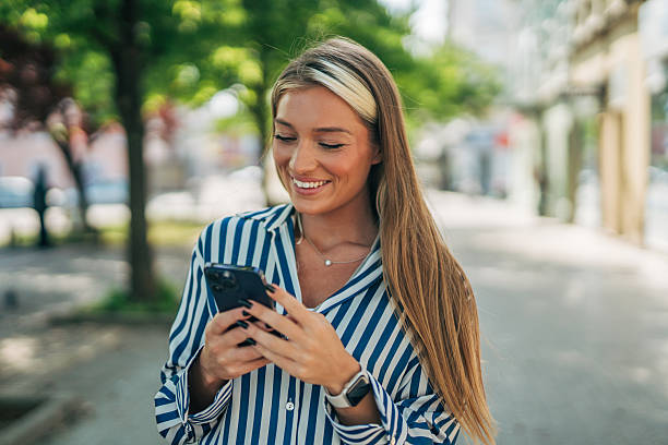 istock Young woman using smartphone while walking in city 2213550790