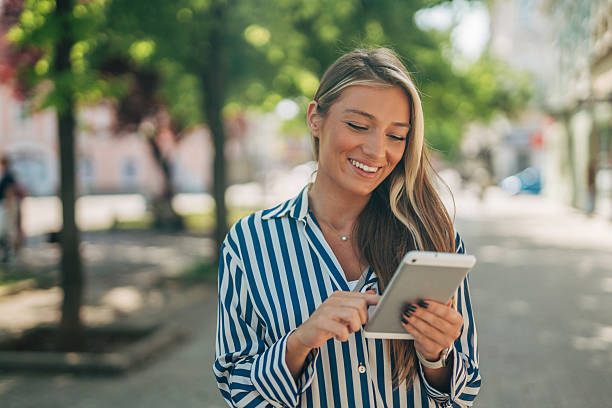 istock Smiling young woman using digital tablet outdoors in urban setting 2213551164