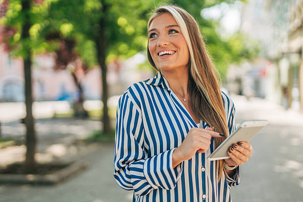 istock Smiling businesswoman using digital tablet while walking in the city 2213551225