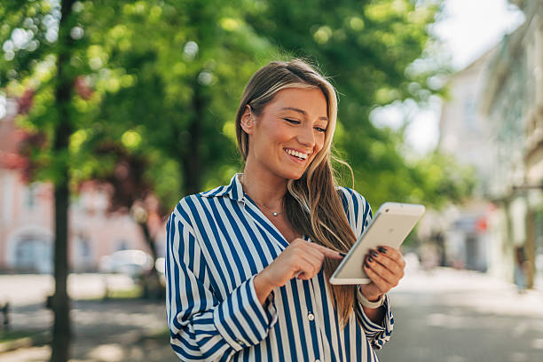 istock Smiling young woman using digital tablet outdoors in urban setting 2213551231