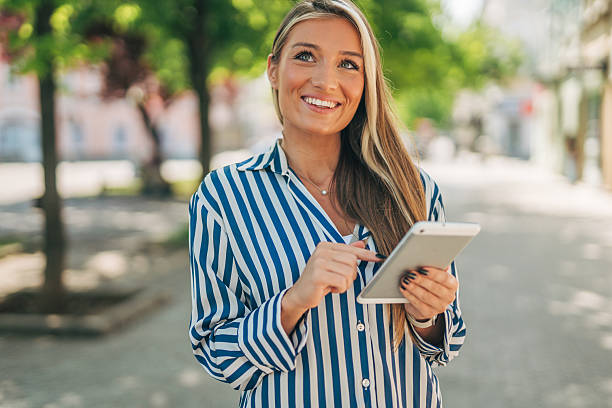 istock Smiling businesswoman using digital tablet outdoors in urban setting 2213551247