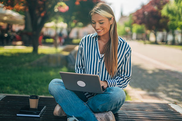 istock Young woman working on laptop in park 2213552567