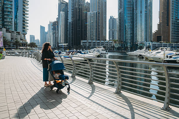 Mother pushing stroller along Dubai Marina promenade