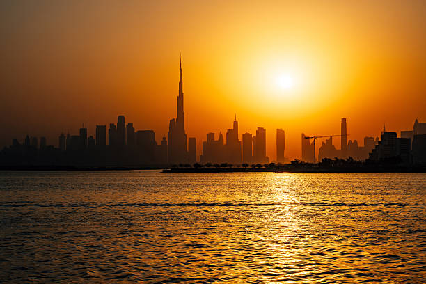 Capturing a dramatic sunset illuminating the Burj Khalifa and the Dubai skyline, showcasing vibrant colors reflecting off tranquil waters