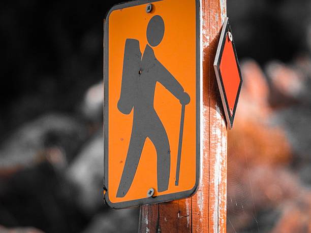 A close-up of a hiking trail sign on a wooden post with a blurred natural background.
