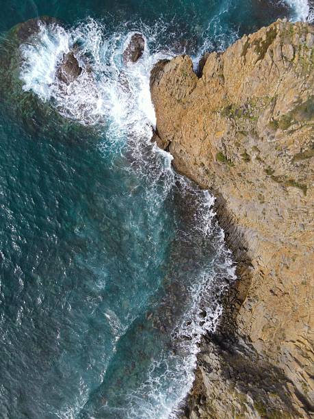 istock Aerial view of waves crashing against rugged cliffs. 2213556155