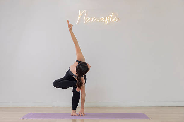 Young woman performing revolved chair pose in yoga studio