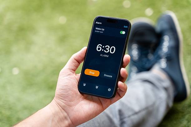 istock Man holding smartphone with alarm clock app 2213560276