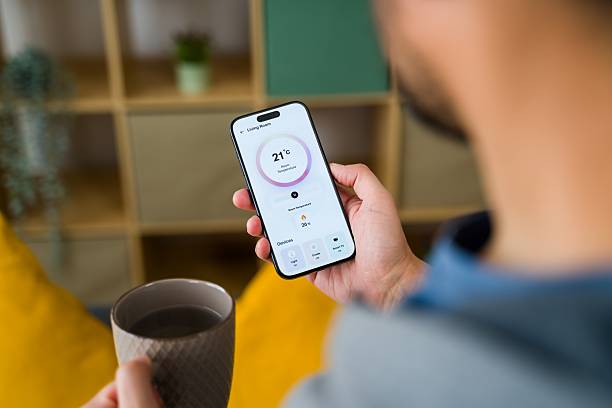 istock Man controlling home temperature with smartphone app and drinking tea 2213561730