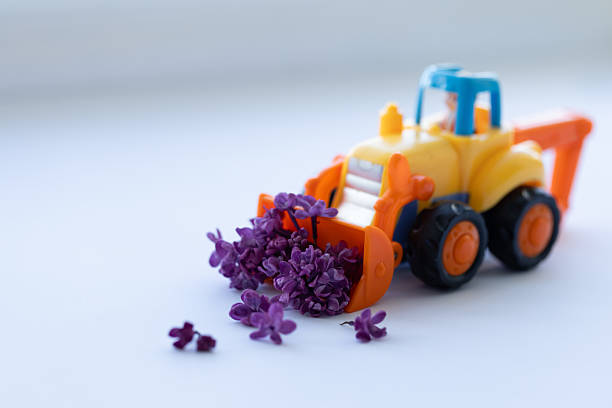 Toy backhoe with lilac flowers. Closeup, selective focus