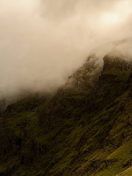 istock Misty clouds envelop towering mountain peaks, creating a serene atmosphere in a quiet highland landscape. Early morning light softly illuminates the lush greenery below. 2213562336
