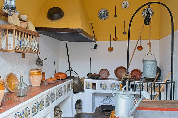 Cordoba, spain - may 5th 2025: rustic spanish kitchen interior featuring hanging cookware and ceramic dishware against whitewashed wall in cordoba