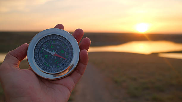 istock Hand holding compass during sunset over river landscape representing navigation and exploration concepts 2213565824