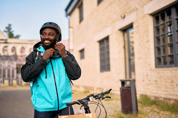 istock Smiling Courier Adjusting Helmet Near Bicycle 2213567585