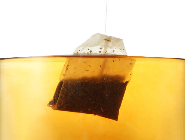 istock Putting tea bag into glass cup on white background, closeup 2213568088