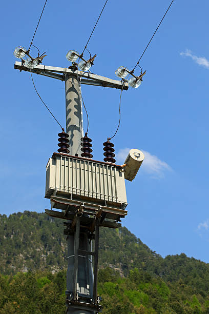 A tall pole with a red and white sign on it. The pole is covered in wires and is surrounded by clouds