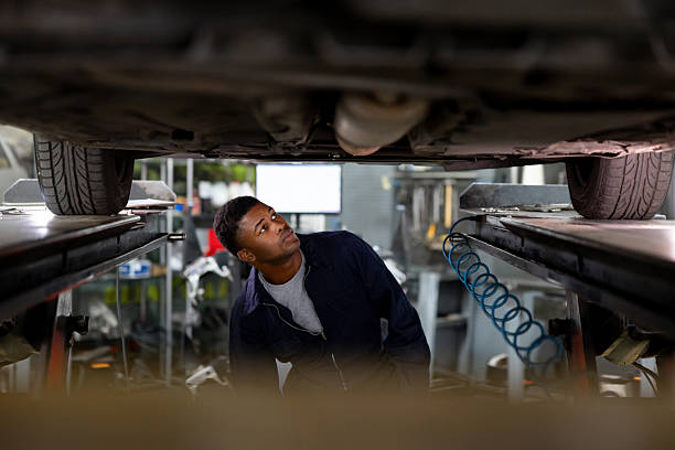 istock Mechanic looking under a vehicle while it's lifted on a car jack 2213571449