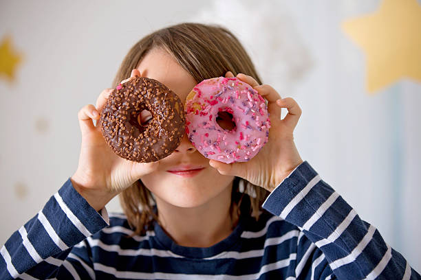 istock Cute sweet blonde child, playing and eating donuts 2213572265
