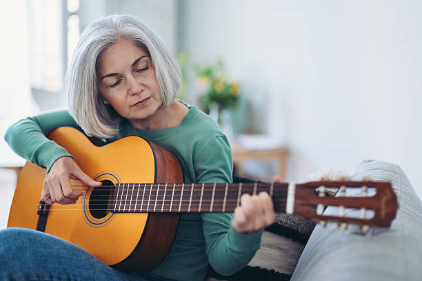 istock Mature woman focused on playing guitar 2213572765