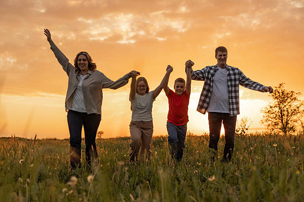 istock Family Joyfully Walking Through Field on sunset 2213574305