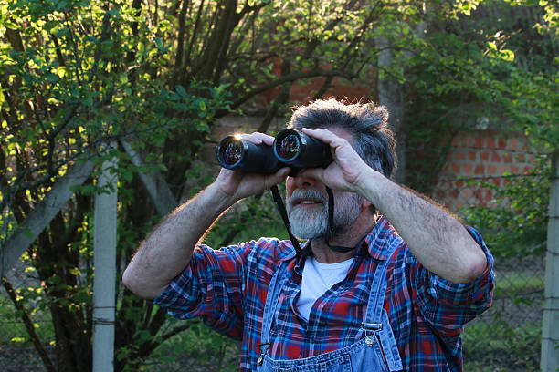 istock Senior silver man looking bird in nature 2213574723