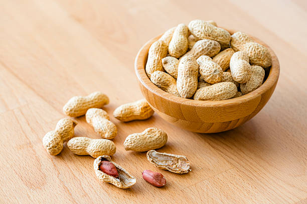 Bowl filled with organic peanuts shot on wood table
