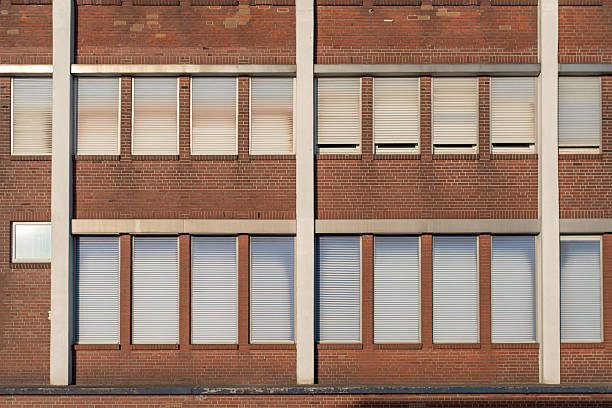 Partial view of a red brick facade with blinds and closed windows