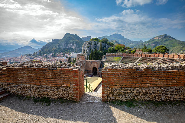 View of the ancient Greek theater in Taormina, Sicily, Italy, with stunning views of the mountains and Mount Etna.