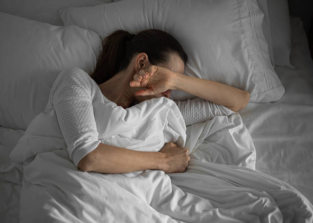 Sleepless woman lying in bed feeling tired stressed.