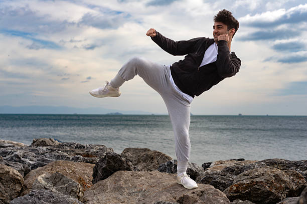 Young man training karate and kickboxing at the beach