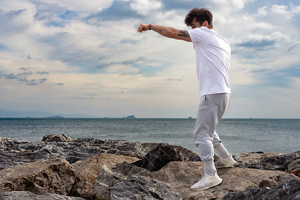 Young man training karate and kickboxing at the beach