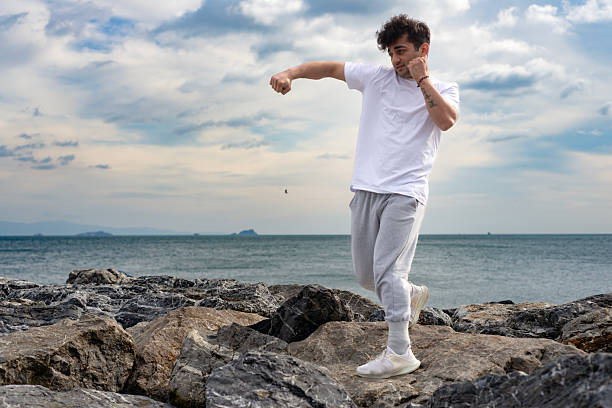 Young man training karate and kickboxing at the beach