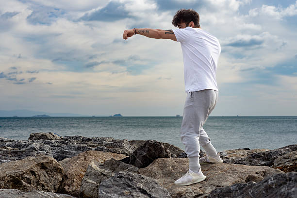 Young man training karate and kickboxing at the beach