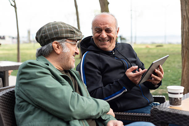 istock Senior friends men talking and using tablet outdoors 2213586510