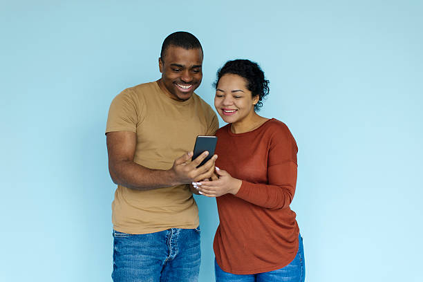 istock Cool App. Excited black couple looking at smartphone screen in hands 2213590474