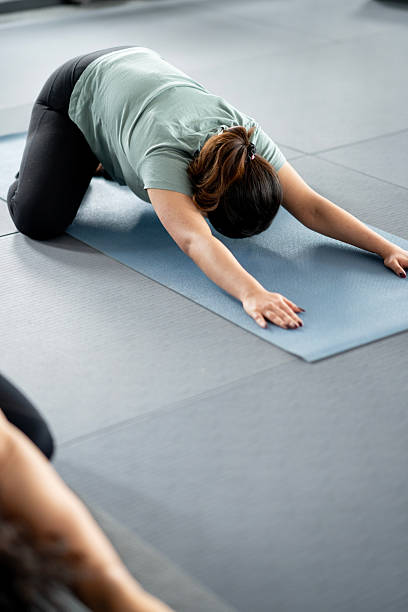 istock Yoga Class Participants Practicing Child's Pose on Mats in a Studio 2213599429