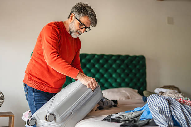 istock senior man pack clothes to suitcase prepare for vacation 2213600075