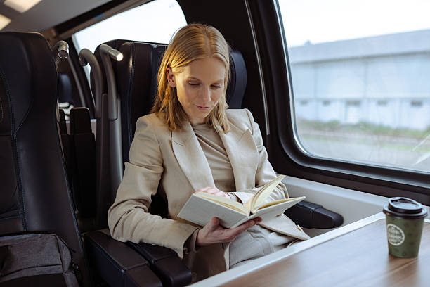 istock Businesswoman reading a book while traveling on a train 2213607751