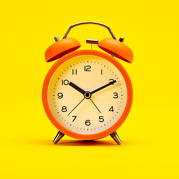 istock Alarm Clock Orange on a Yellow Background 2213613901
