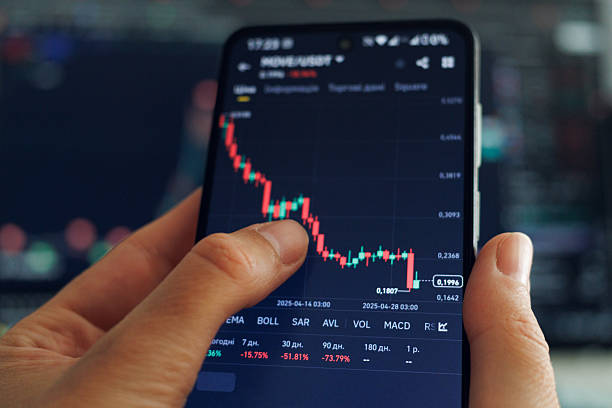 istock A person's hands hold a smartphone displaying a declining cryptocurrency trading chart with predominantly red candlesticks. 2213627048