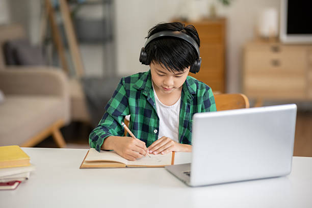 istock A boy is studying online intently on his laptop at home. 2213633569