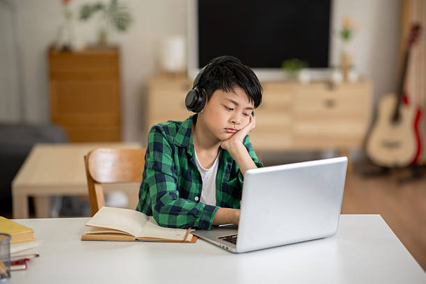 istock A boy is studying online intently on his laptop at home. 2213633599