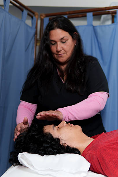 istock Therapist performing reiki healing treatment on patient lying on massage table 2213646171