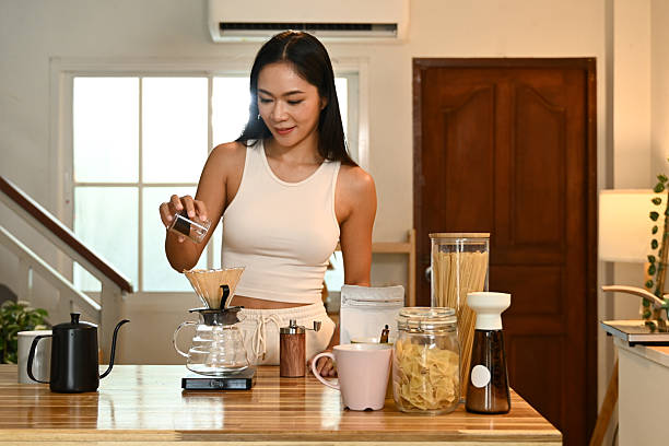 istock A woman is making coffee and pouring it into a cup. The scene is set in a kitchen with various items on the counter. 2213652770