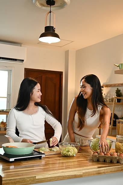 istock Two women are in a kitchen, laughing and talking while preparing food. 2213652858