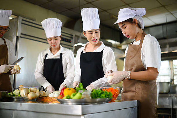 istock Cooking school instructor explaining food preparation techniques to students in a kitchen 2213654970