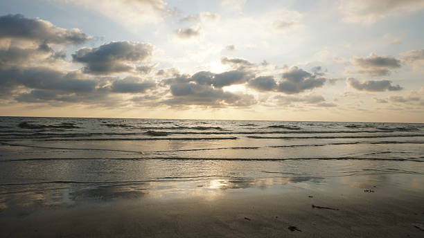 istock Sunset reflecting on wet sand with incoming waves and cloudy sky 2213656417